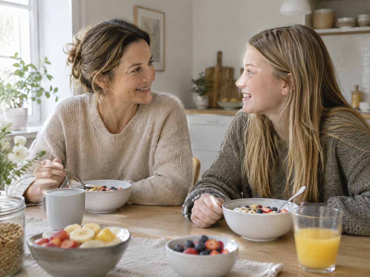 Moeder en tienerdochter praten en lachen samen aan de ontbijttafel